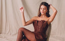 Woman sitting and playing with her hair while wearing a brown LPA mini dress.